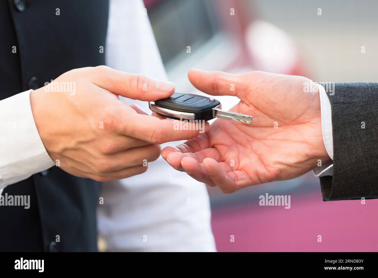 Closeup Of Valet's Hand Giving Car Key To Businessperson Stock Photo