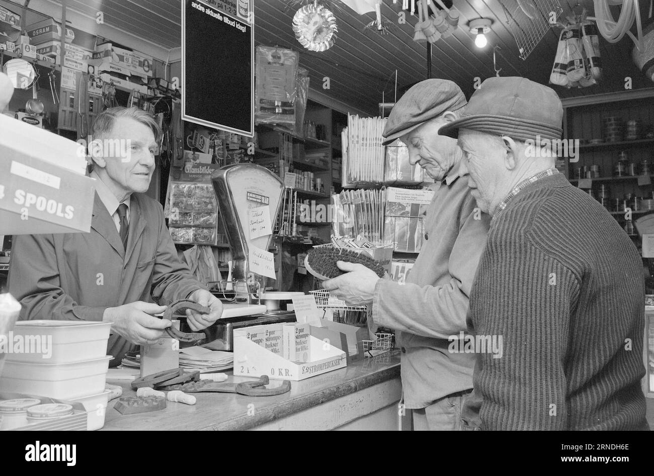 Actual 03 - 4 - 1974: Kjöpmann's protest against the chaseTake it easy at E18 Land trader Bjarne Eriksen will keep the conversation going over the counter. Hence the sign 'Take it easy buy'.  Eriksen's rarer range of goods is assessed with the knowledge of pensioners Erling Bjørnstad and Olaves Smerkerud, former blacksmiths in the village. They take a trip to the store every day. SAs the pictures show, there is nothing to say about the product selection at Eriksen.  Photo: Ivar Aaserud / Aktuell / NTB ***PHOTO NOT IMAGE PROCESSED*** This text has been automatically translated! Stock Photo