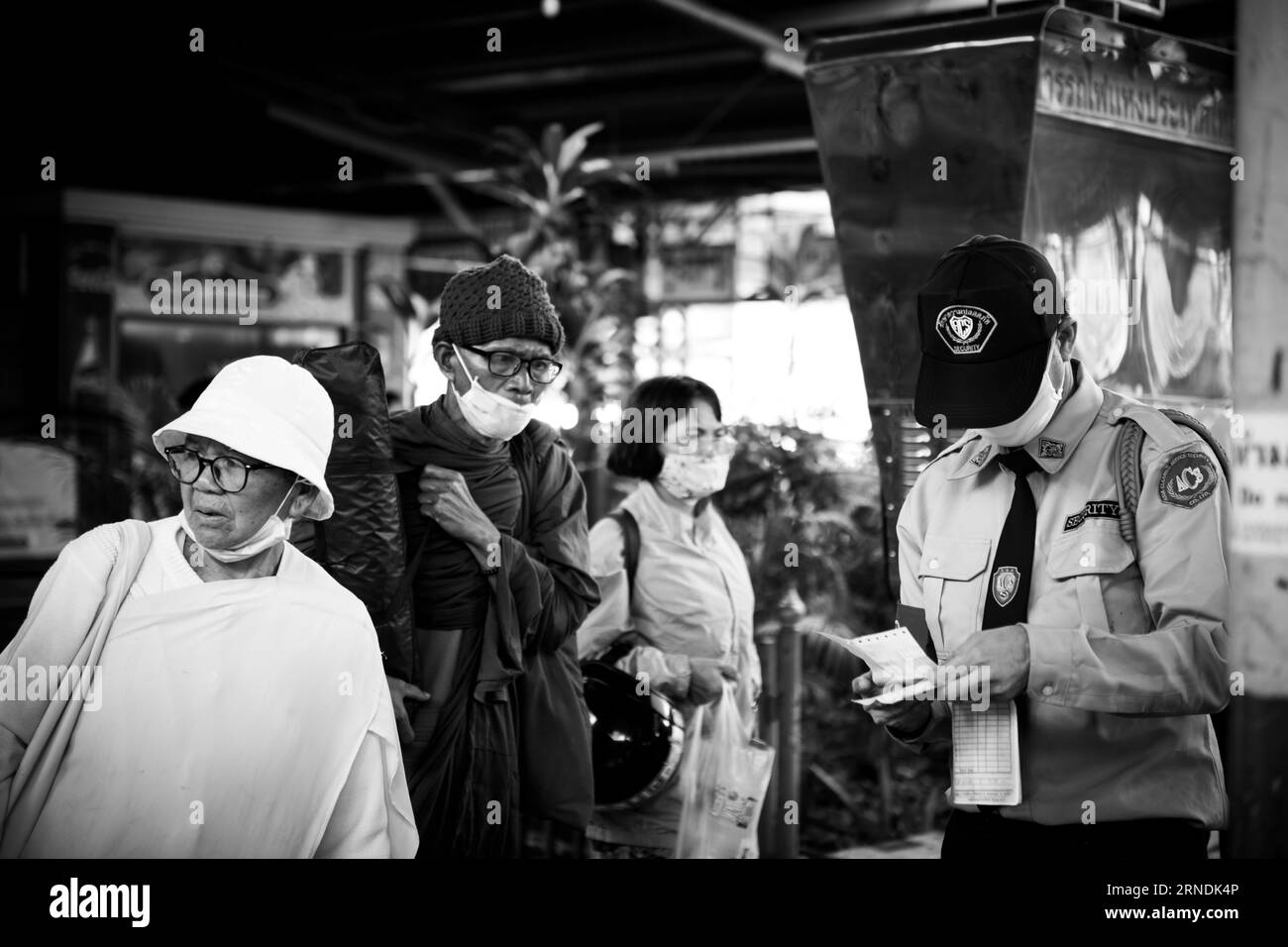 A platform attendant at Hua Lamphong Railway Station in Bangkok captured holding and examining a ticket while assisting travelers. Stock Photo
