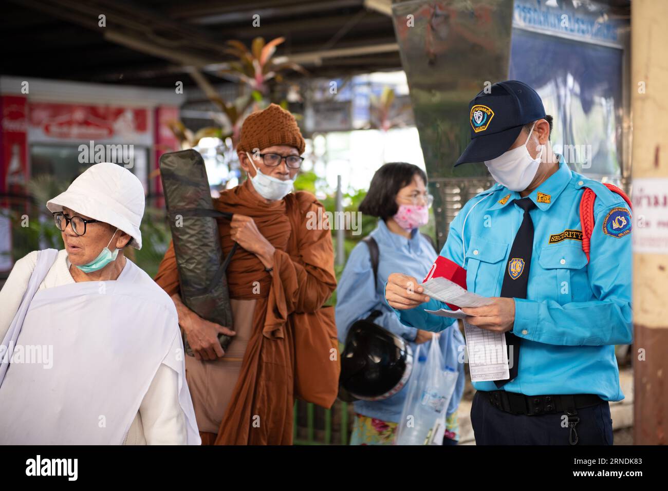 In this focused shot, a platform attendant at Hua Lamphong Railway Station in Bangkok holds and examines a ticket while assisting a passenger. The ima Stock Photo