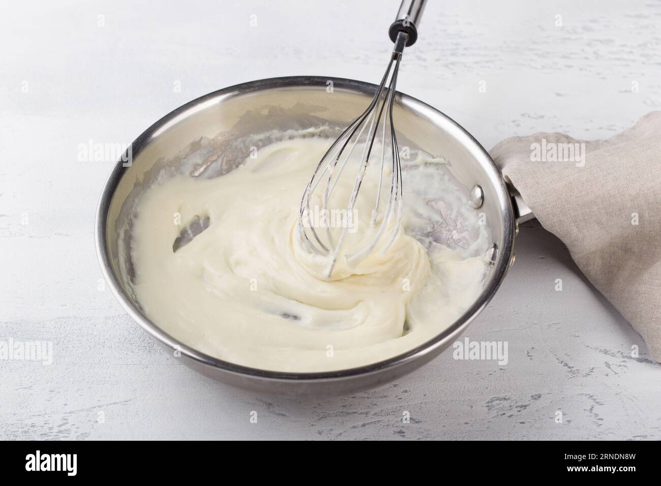 Making cheese sauce for pasta. Add milk and mix until creamy. DIY step by step step 6 Stock Photo