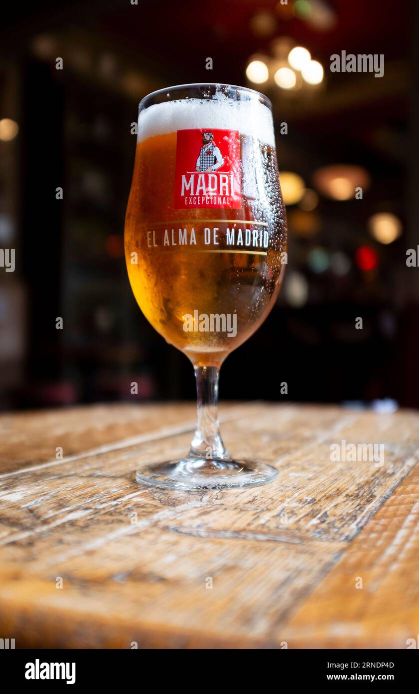 Pint of cold Madrí Excepcional lager beer standing on wooden table Stock Photo