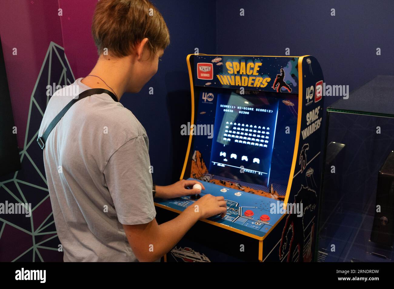 Space invaders Taito game machine. Simple Space Arcade in 8-bit retro video old game. Boy plays classic slot machine. Warsaw, Poland - July 28, 2023. Stock Photo