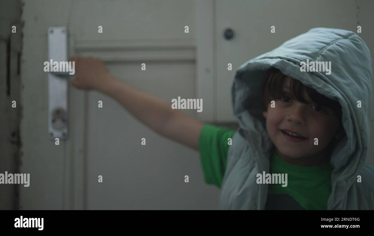 Happy child opening front door while holding doorknob, Little Boy in