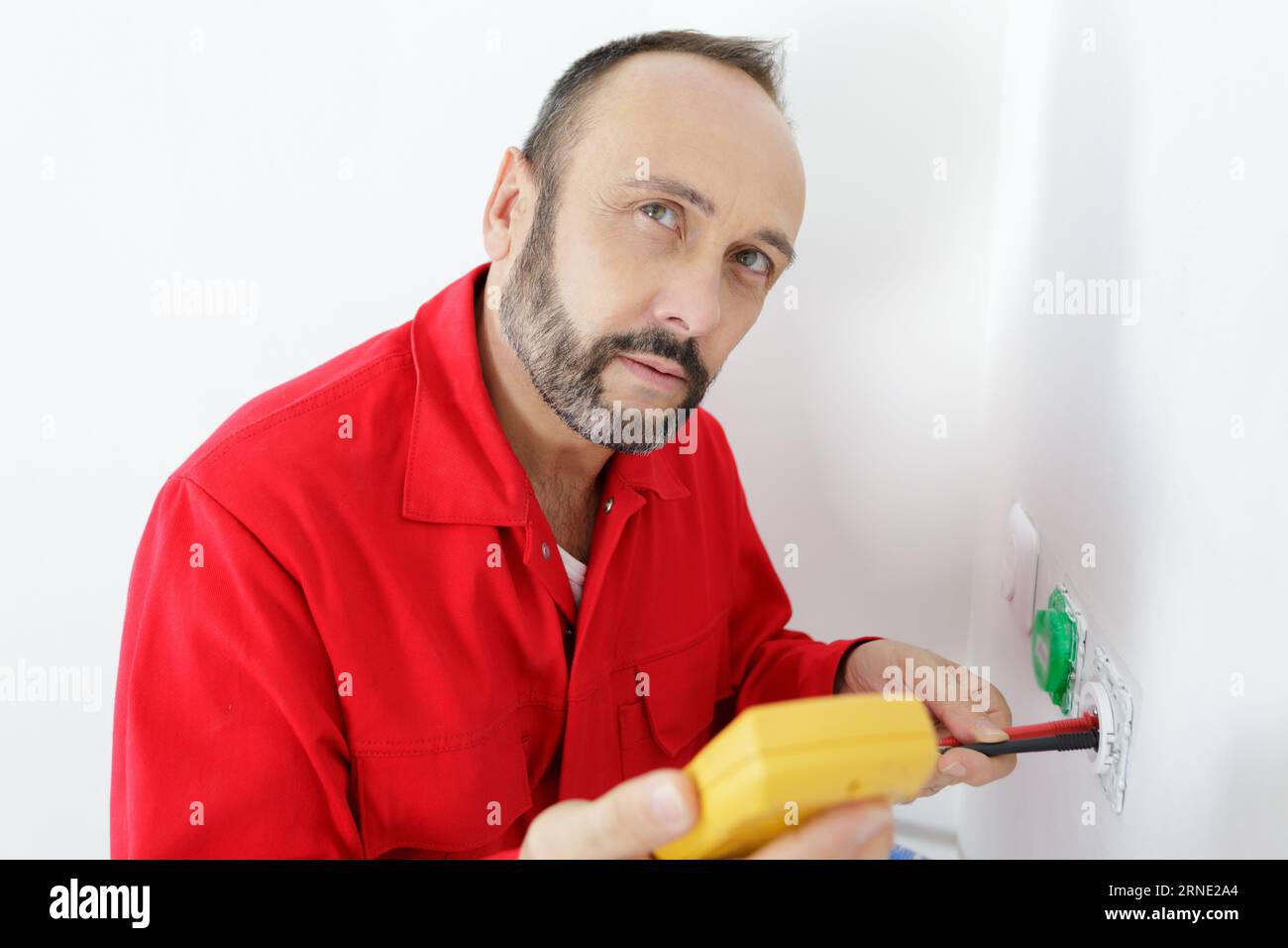 electrician a wall socket with electronic multimeter Stock Photo