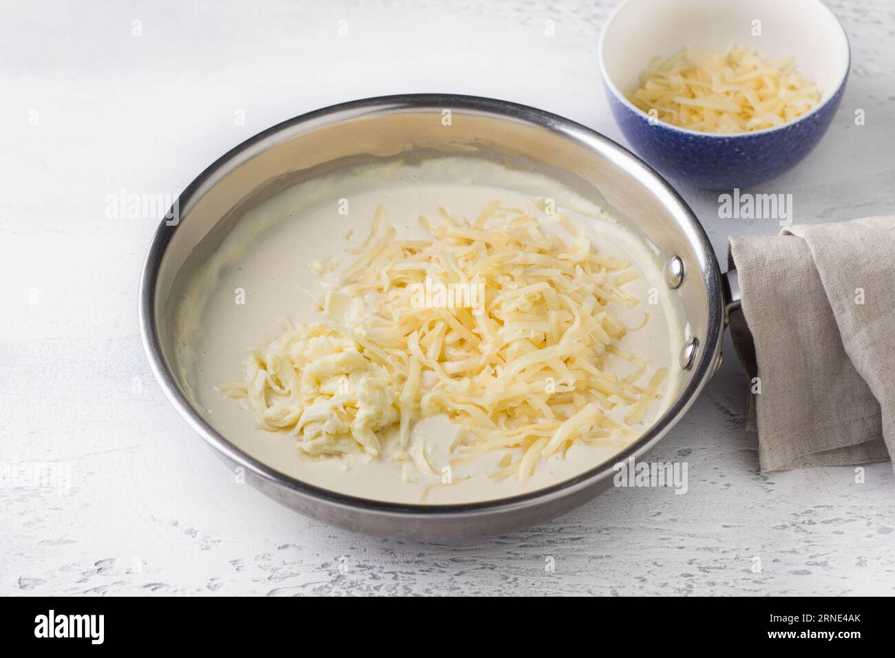 Making cheese sauce for pasta. Add grated cheese and stir. DIY step by step step 8 Stock Photo