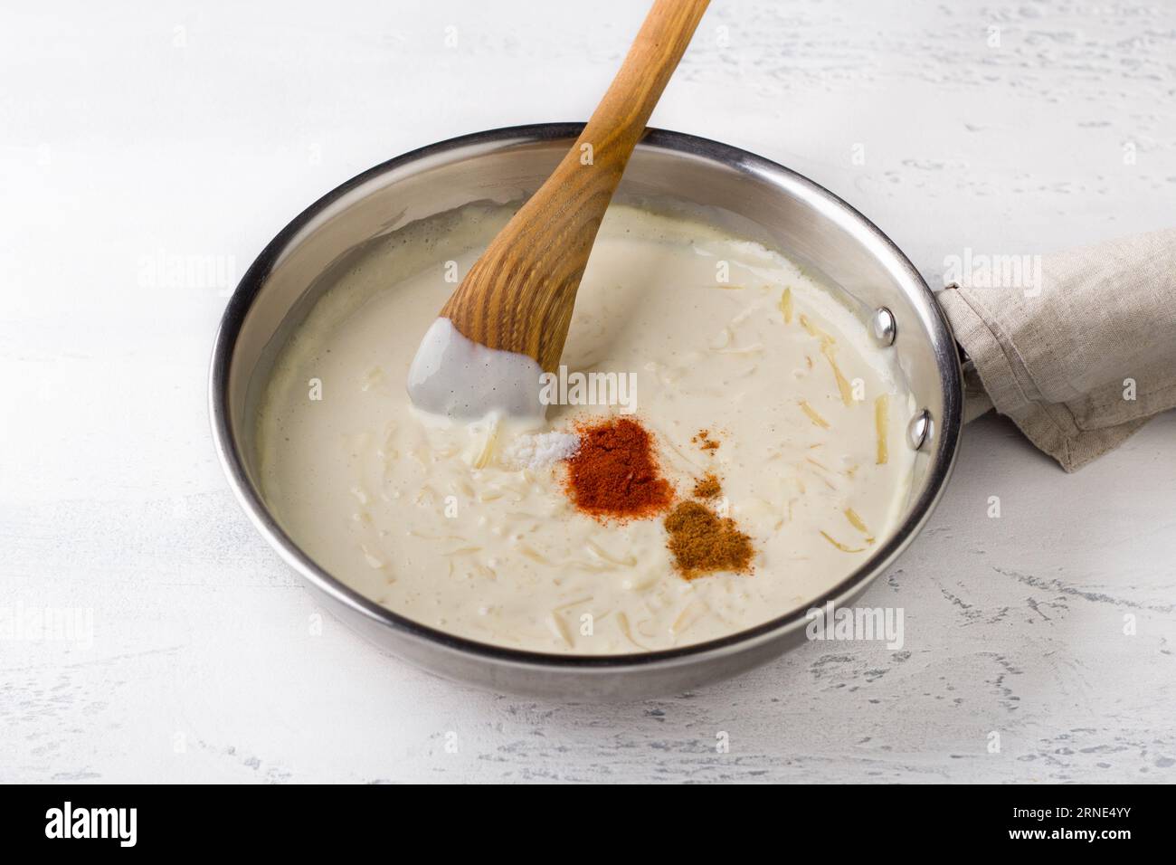 Making cheese sauce for pasta. Add spices: salt, nutmeg and sweet paprika, and stir with a wooden spatula. DIY, step by step, step 9 Stock Photo