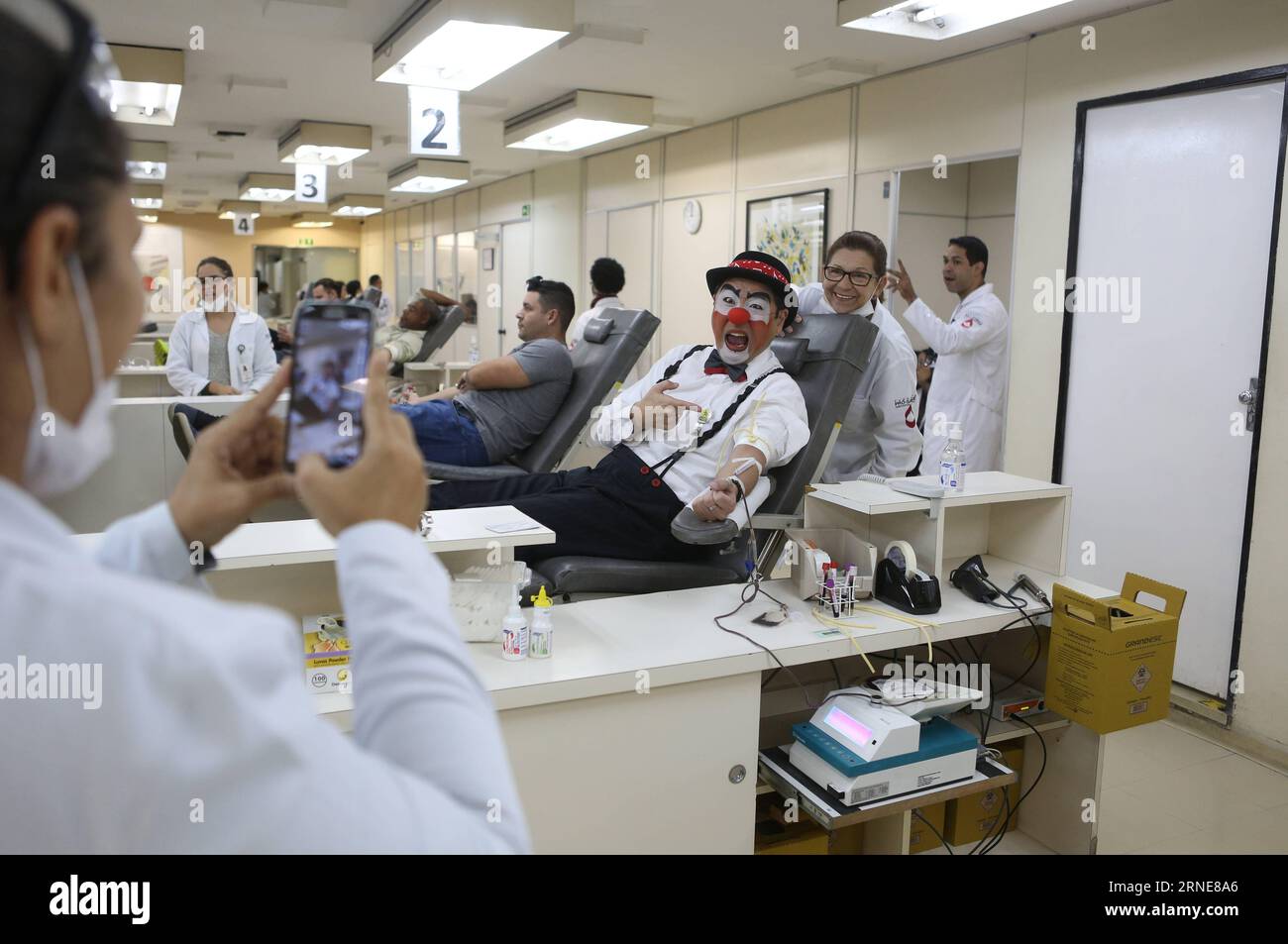 (160614) -- SAO PAULO, June 14, 2016 -- Image taken on June 9, 2016 shows a nurse taking photos of Gilberto Kido (C), 50, while doing a voluntary blood donation at the Pro Sangre Foundation in Sao Paulo, Brazil. Gilberto Kido has been a voluntary blood donor for the last 30 years after his mother died while waiting for a kidney transplant. Using his clown character, Kido has an objective to encourage the blood donation for saving lives. The World Blood Donor Day is celebrated every year on June 14. In 2016 the theme of the campaign is Blood connects us all , the World Health Organization (WHO) Stock Photo