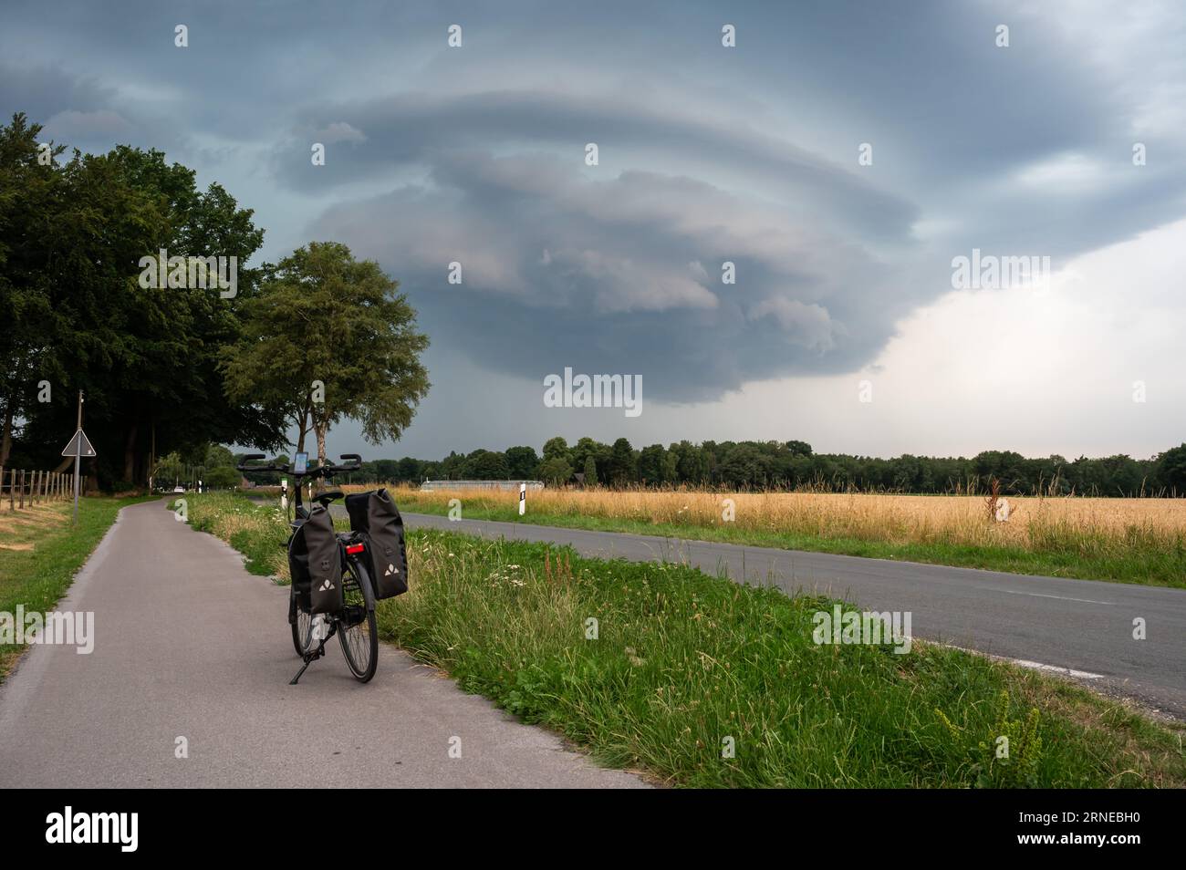 Walbeck, North Rine-Westphalia, Germany, July 14, 2023 - Trekking bike at a country road with a hugh cumulus rain cloud in the background Stock Photo
