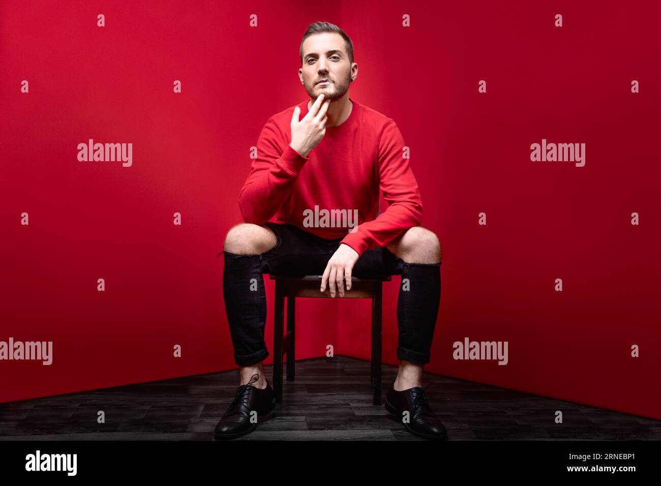 self addicted man in red studio sit in chair look straight into camera