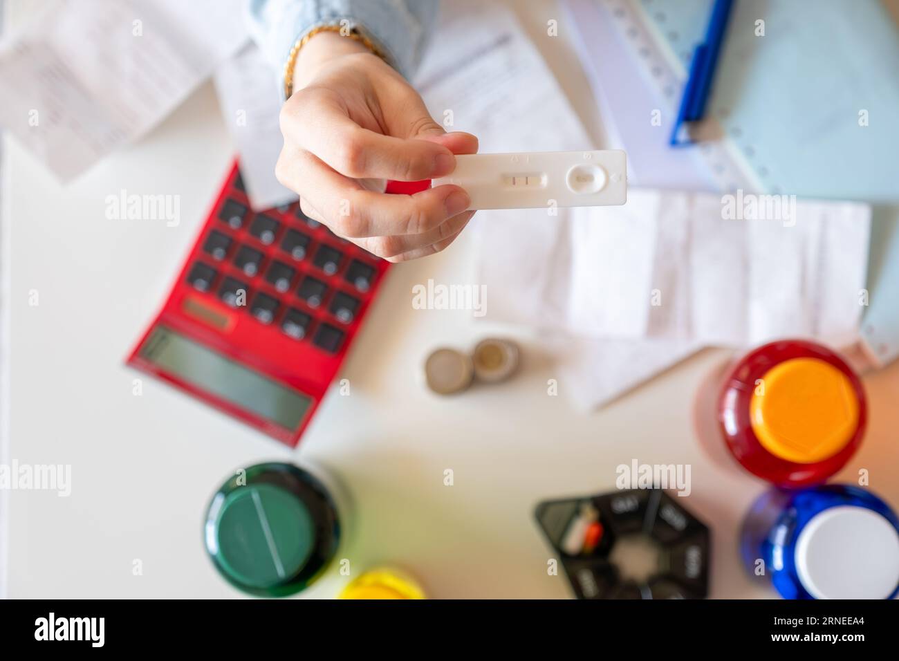 Female hand holding pregnancy tests with receipts and calculator in the