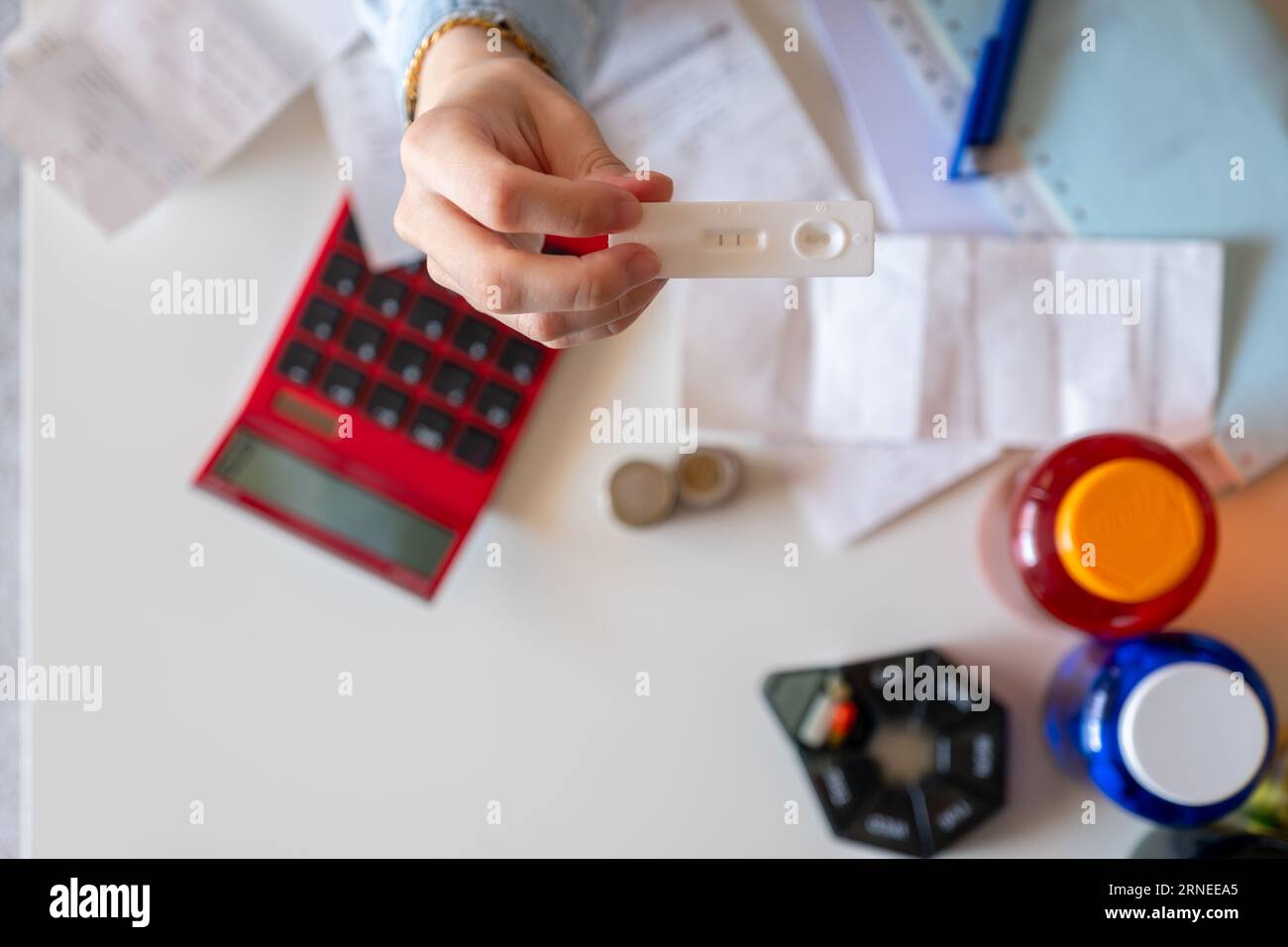 Female hand holding pregnancy tests with receipts and calculator in the