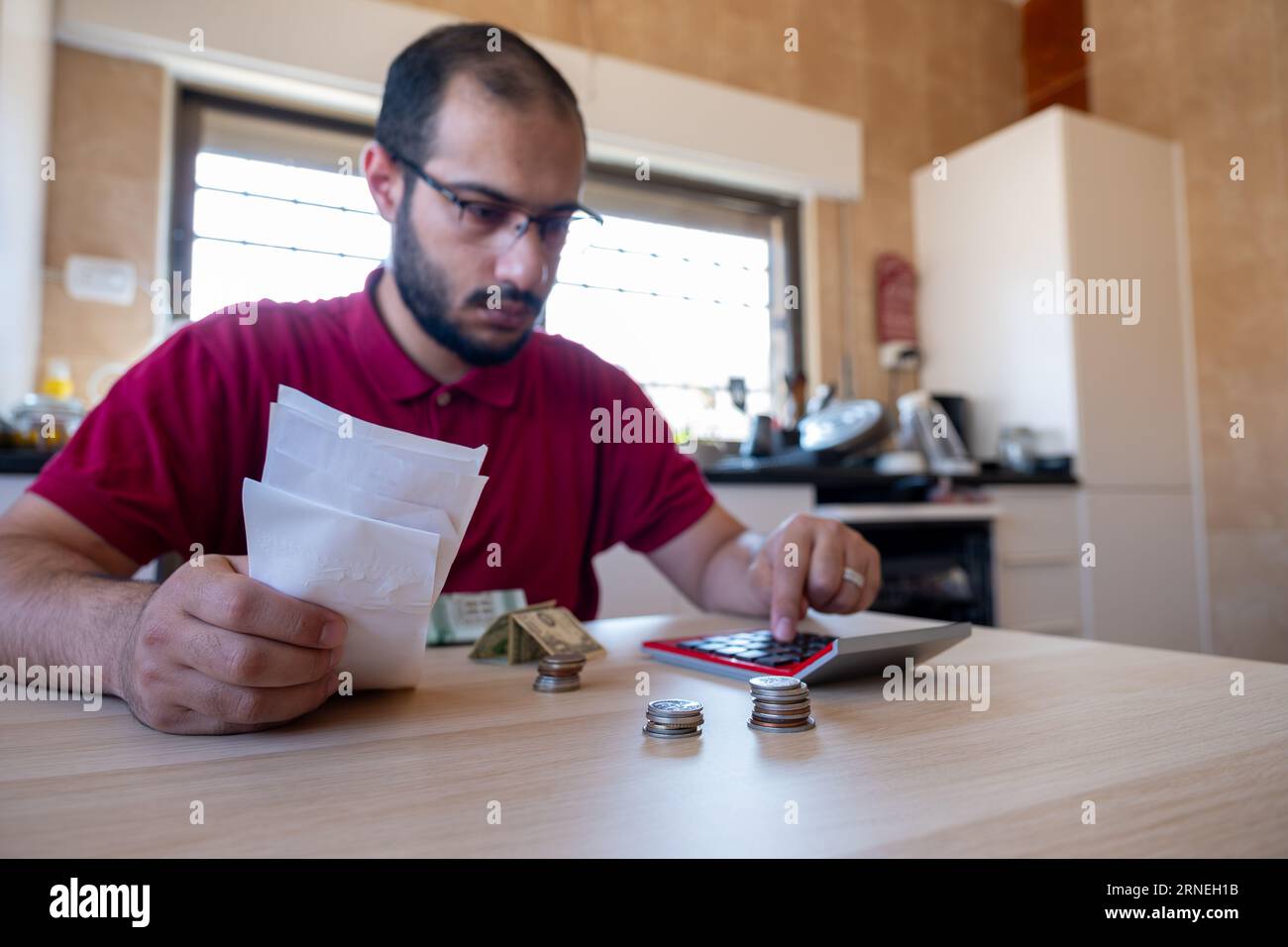 man sitting in the kitchen and calculating the costs of living feeling frustrated Stock Photo