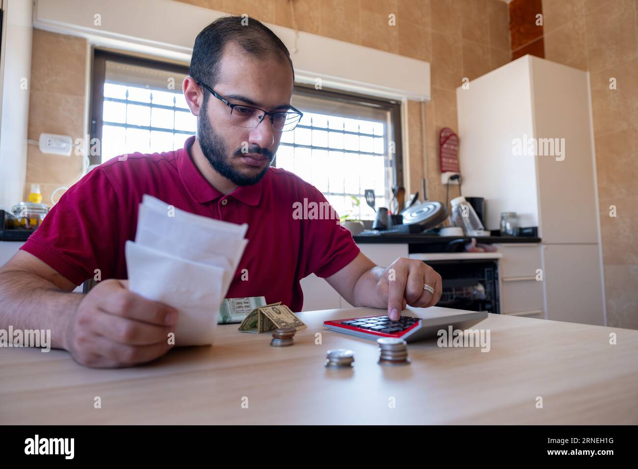 man sitting in the kitchen and calculating the costs of living feeling frustrated Stock Photo