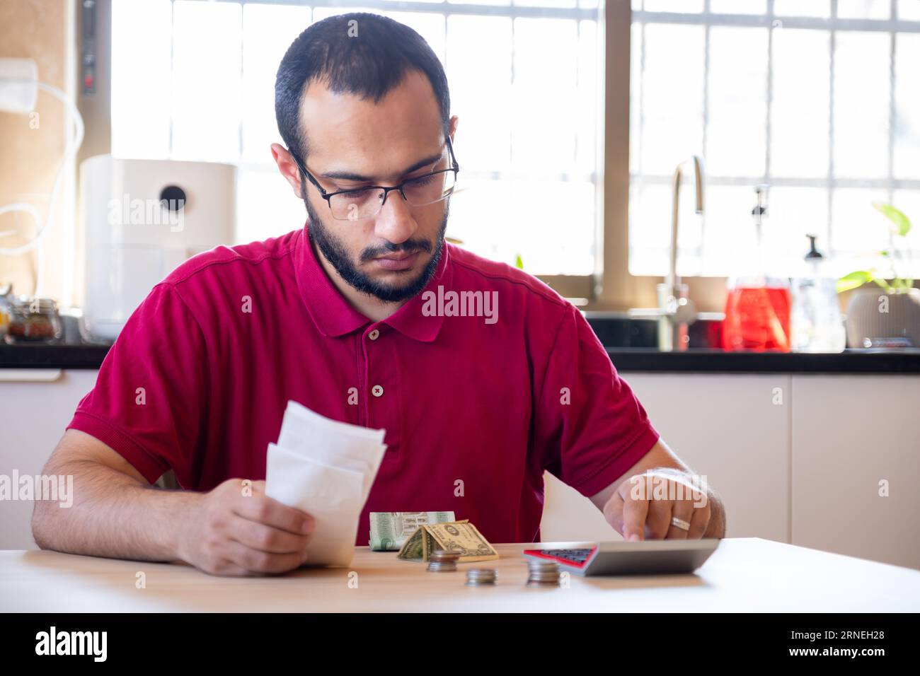 man sitting in the kitchen and calculating the costs of living feeling frustrated Stock Photo