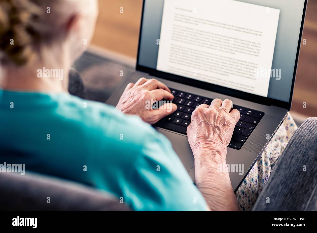 Old senior woman using laptop computer to write text. Book, testament, letter or journal. Elder writer with notebook pc. Mature lady working from home. Stock Photo