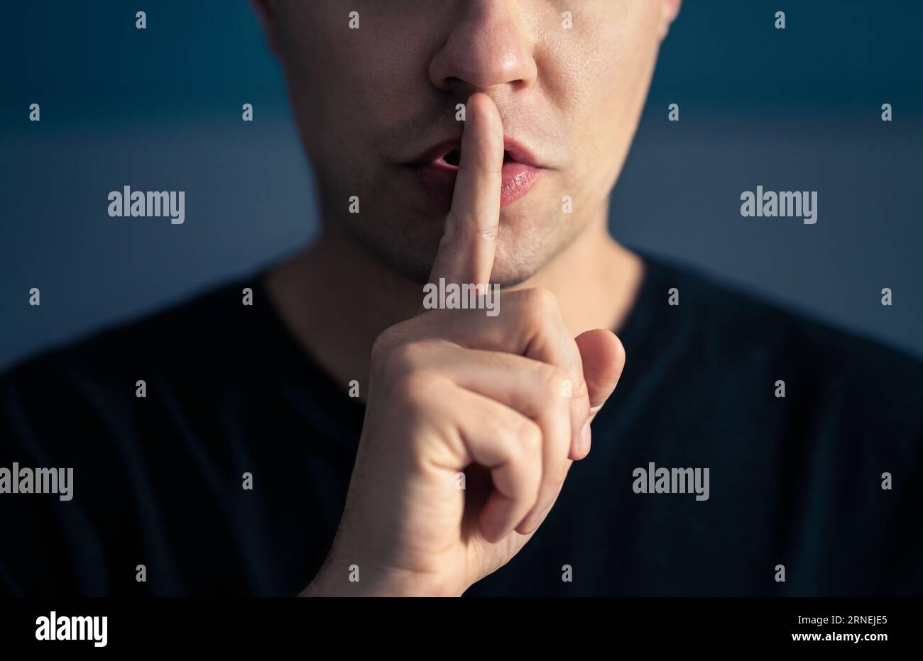 Secret and silence. Quiet silent shh gesture with finger on lips. Man doing expression with hand on mouth. Taboo topic, censorship or freedom. Stock Photo