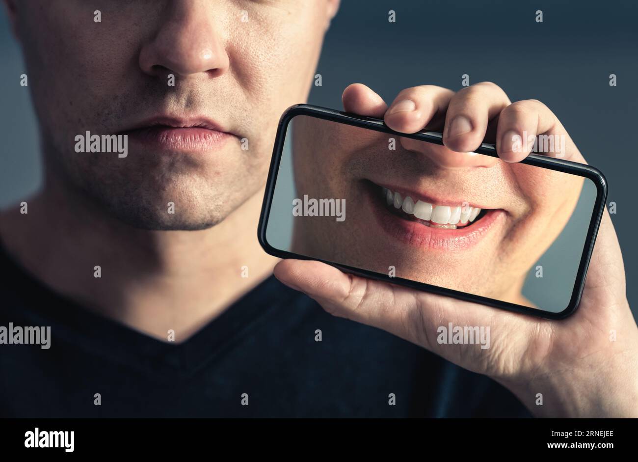 Fake social media smile or filter. Sad face and happy in phone screen. Mental health, depression online and technology concept. Man with anxiety. Stock Photo