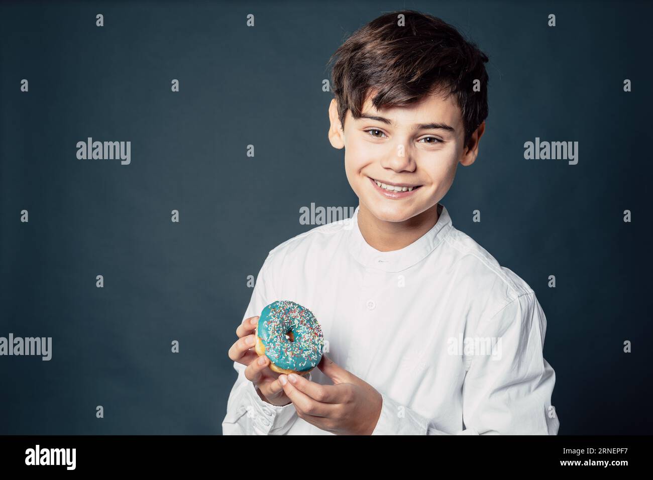 teen boy present donut for camera and is happy about sugar snack that makes his childhood joyful and sweet Stock Photo