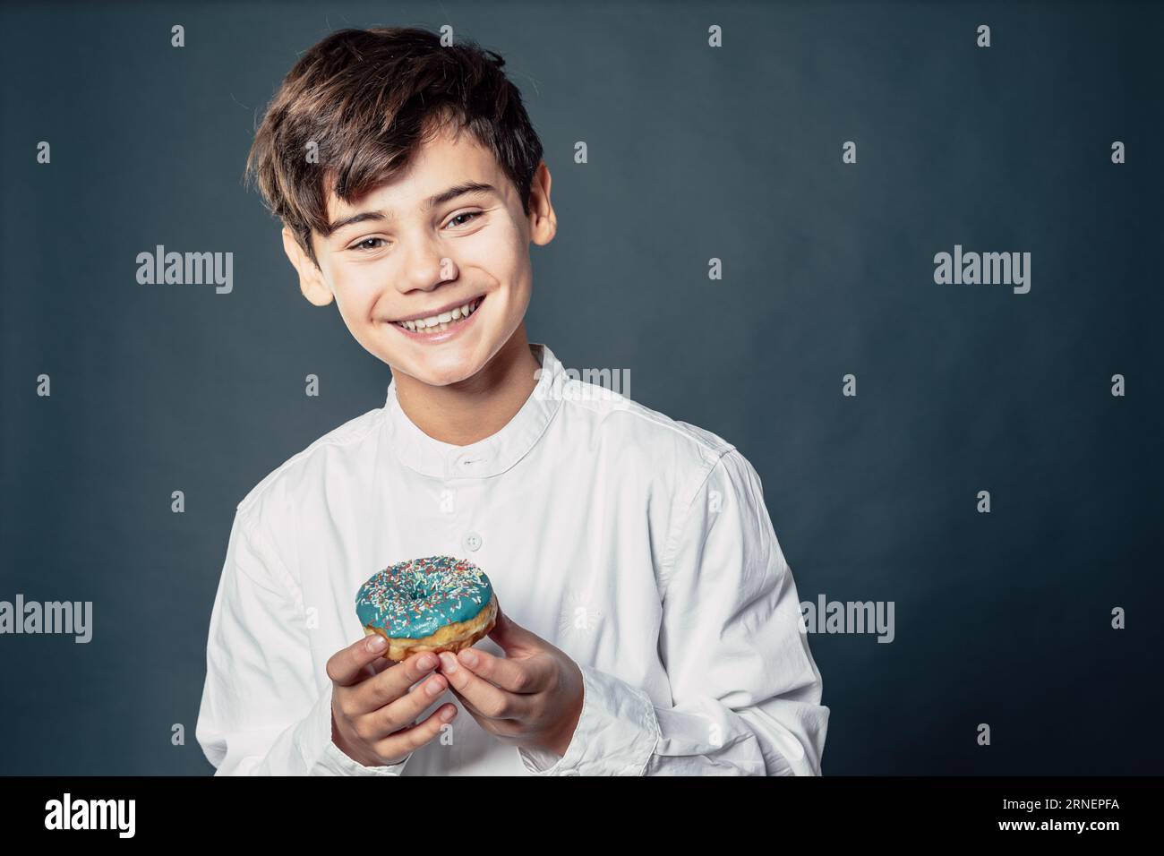 teen boy with donut is happy about sugar snack that makes his childhood joyful and sweet Stock Photo
