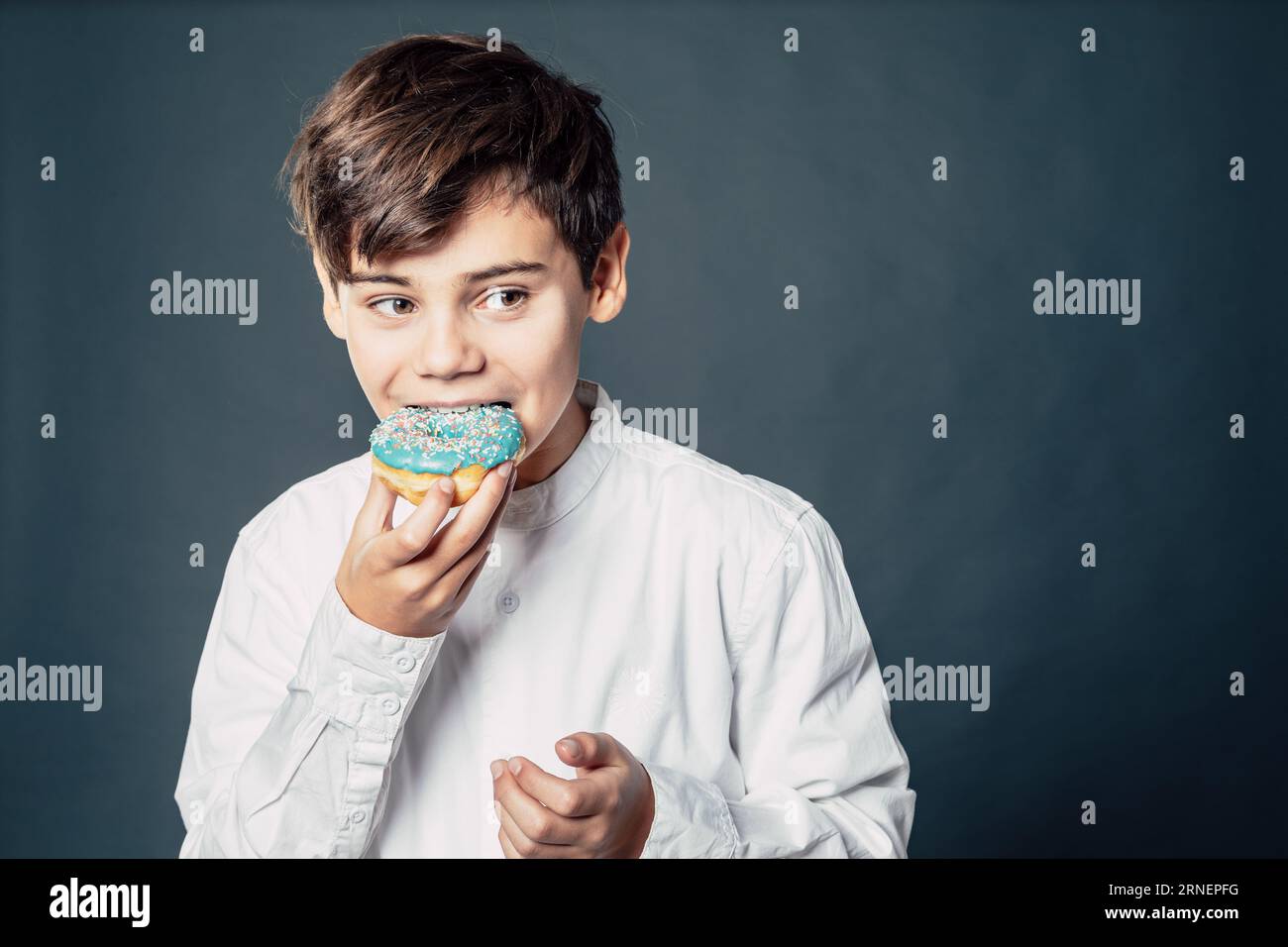teen boy bite and taste blue donut while he is enjoying the sugar rush of his childhood Stock Photo