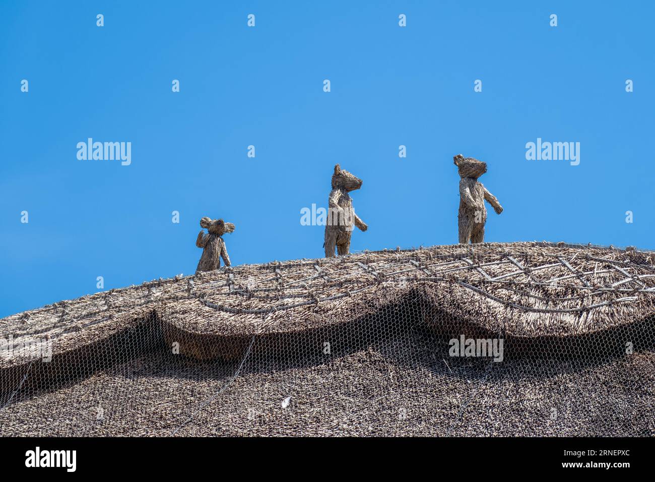 three bears straw finials on the top of a thatched roof with blue sky