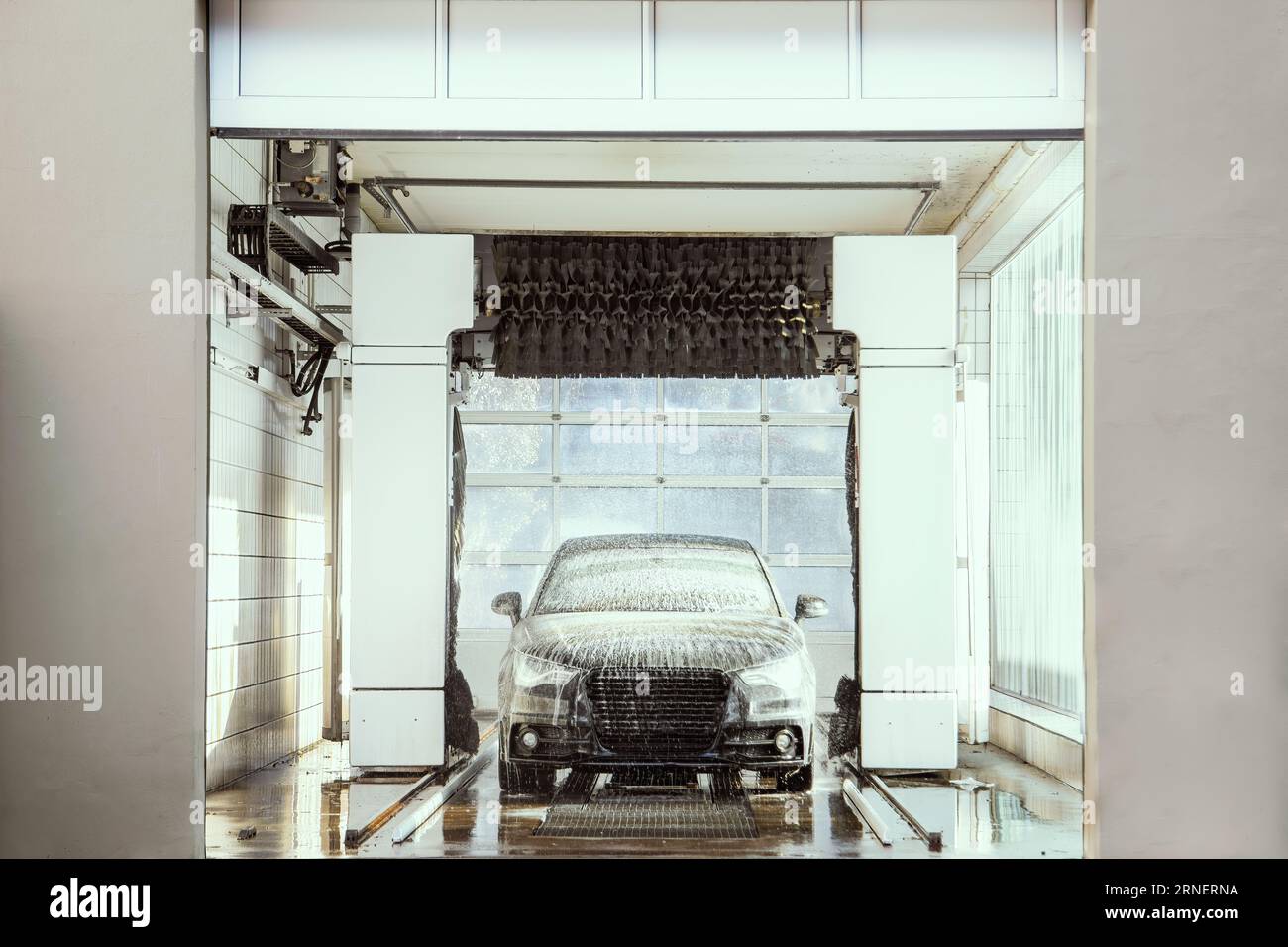 car wash automat with black vehicle drive through washing machine while