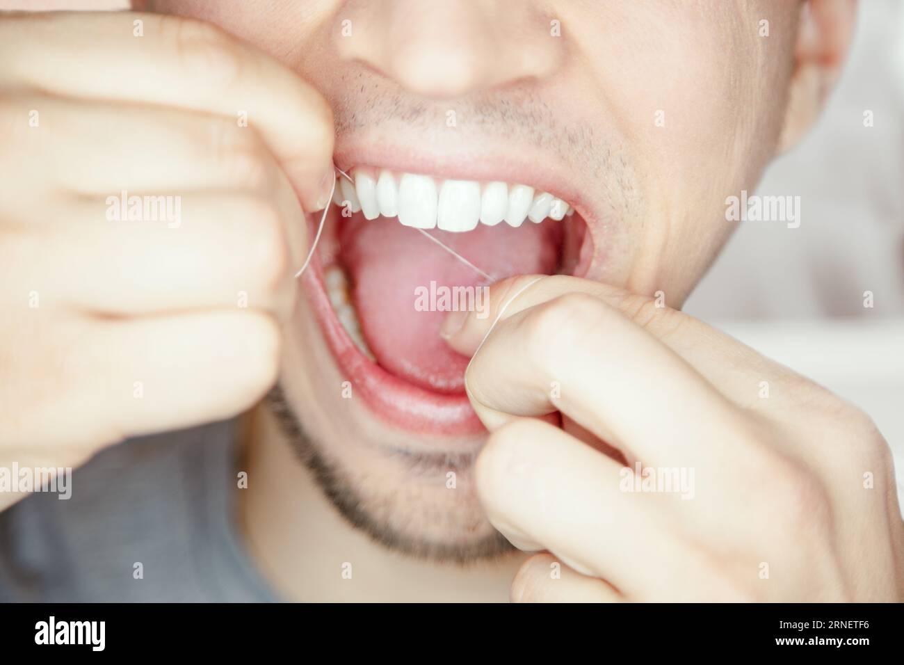 proper floos of your teeth and gum cleans and dislodges food stuck between your teeth, which reduces the amount of bacteria and plaque in your mouth Stock Photo