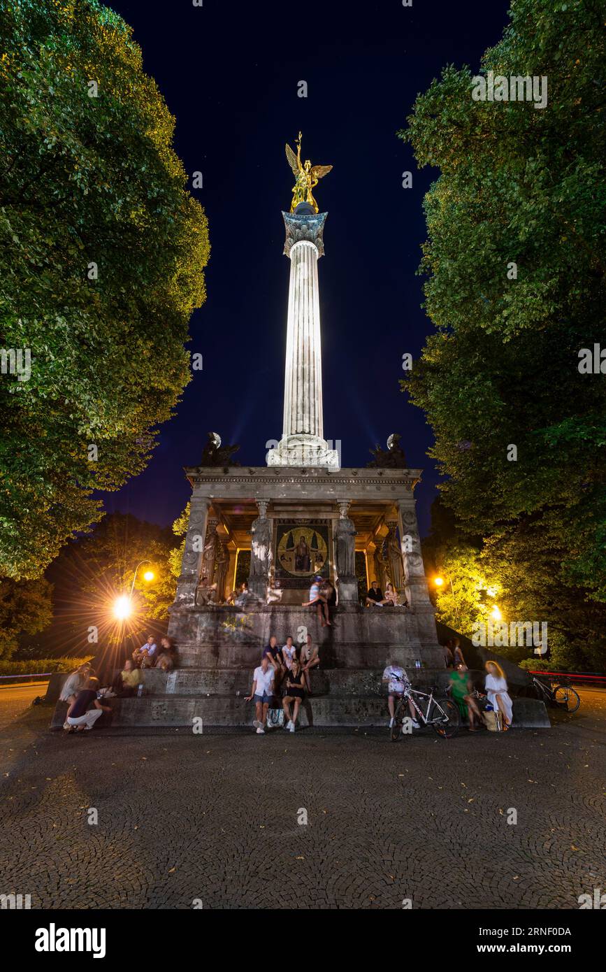 People sitting at the pillar at the temple with the Angel of Peace in nocturnal illumination, Bogenhausen, Munich, Germany Stock Photo