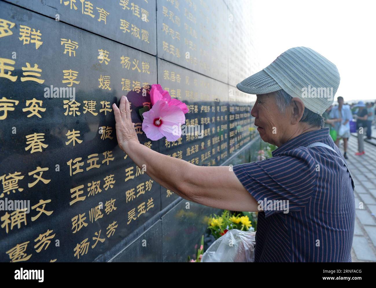 (160728) -- TANGSHAN, July 28, 2016 -- A woman pastes paper flowers beside the name of her relative killed in the 1976 Tangshan earthquake listed on a memorial wall in Tangshan, north China s Hebei Province, July 28, 2016. Local residents came to the Tangshan Earthquake Ruins Memorial Park on Thursday to mark the 40th anniversary of the devastating earthquake that killed their family members and friends. )(wsw) CHINA-HEBEI-TANGSHAN-EARTHQUAKE-COMMEMORATION (CN) MouxYu PUBLICATIONxNOTxINxCHN   160728 Tang Shan July 28 2016 a Woman pastes Paper Flowers Beside The Name of her relative KILLED in T Stock Photo