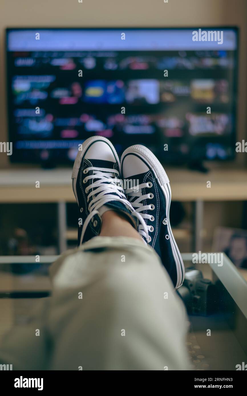 Unrecognizable Person Relaxing At Home Watching TV. View Streaming Services For Entertainment On TV. Choice Of TV Series And Movies Stock Photo