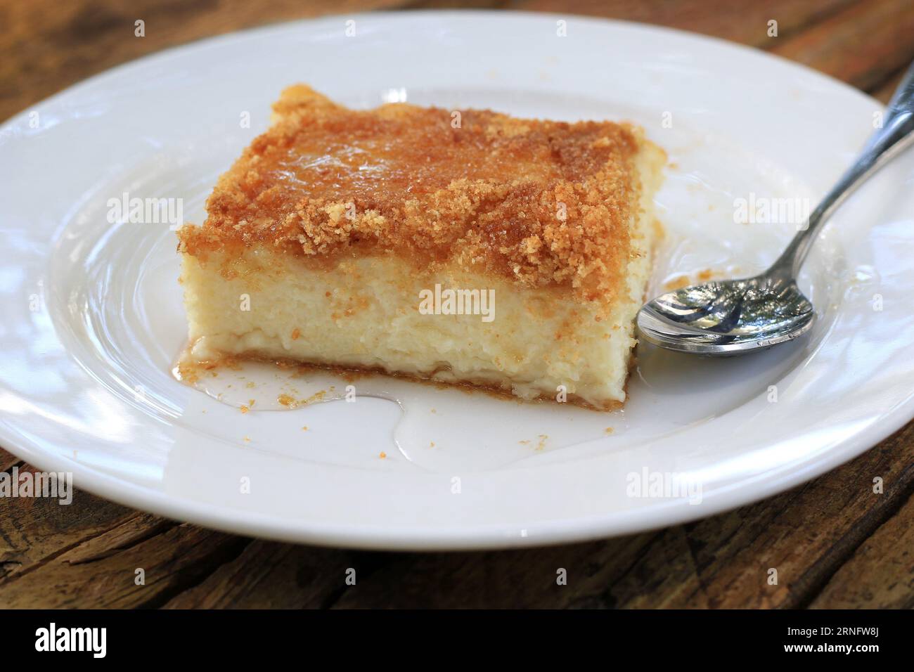 A Knefeh slice in a white plate with plentry of syrup. Stock Photo