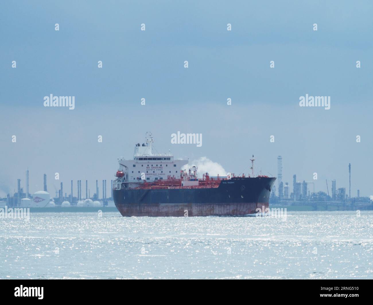 Oil tanker ship sailing past Dow Chemical plant located near Breskens, Zeeland, the Netherlands. Stock Photo