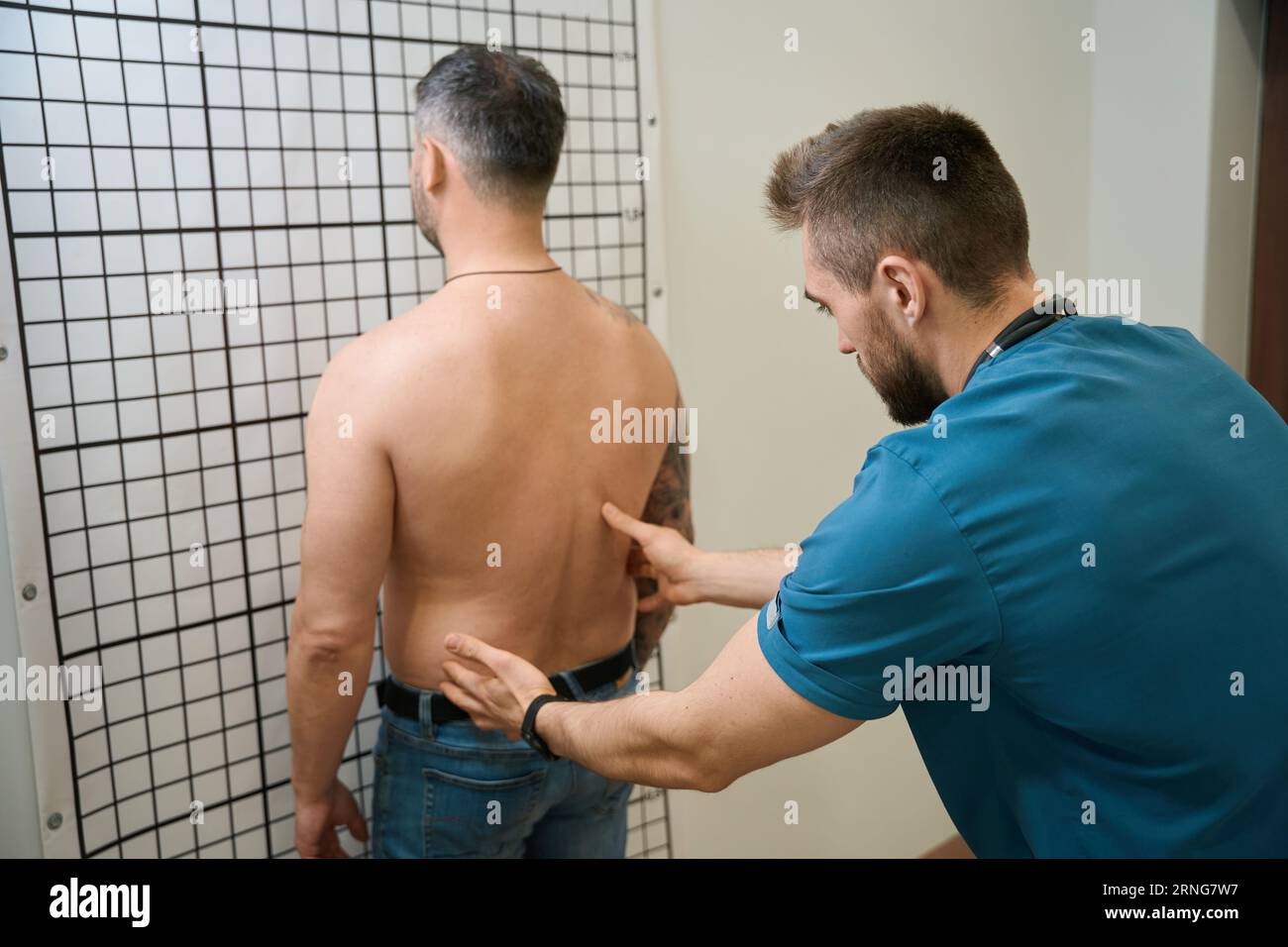 Experienced physical therapist conducting spinal palpation in patient Stock Photo