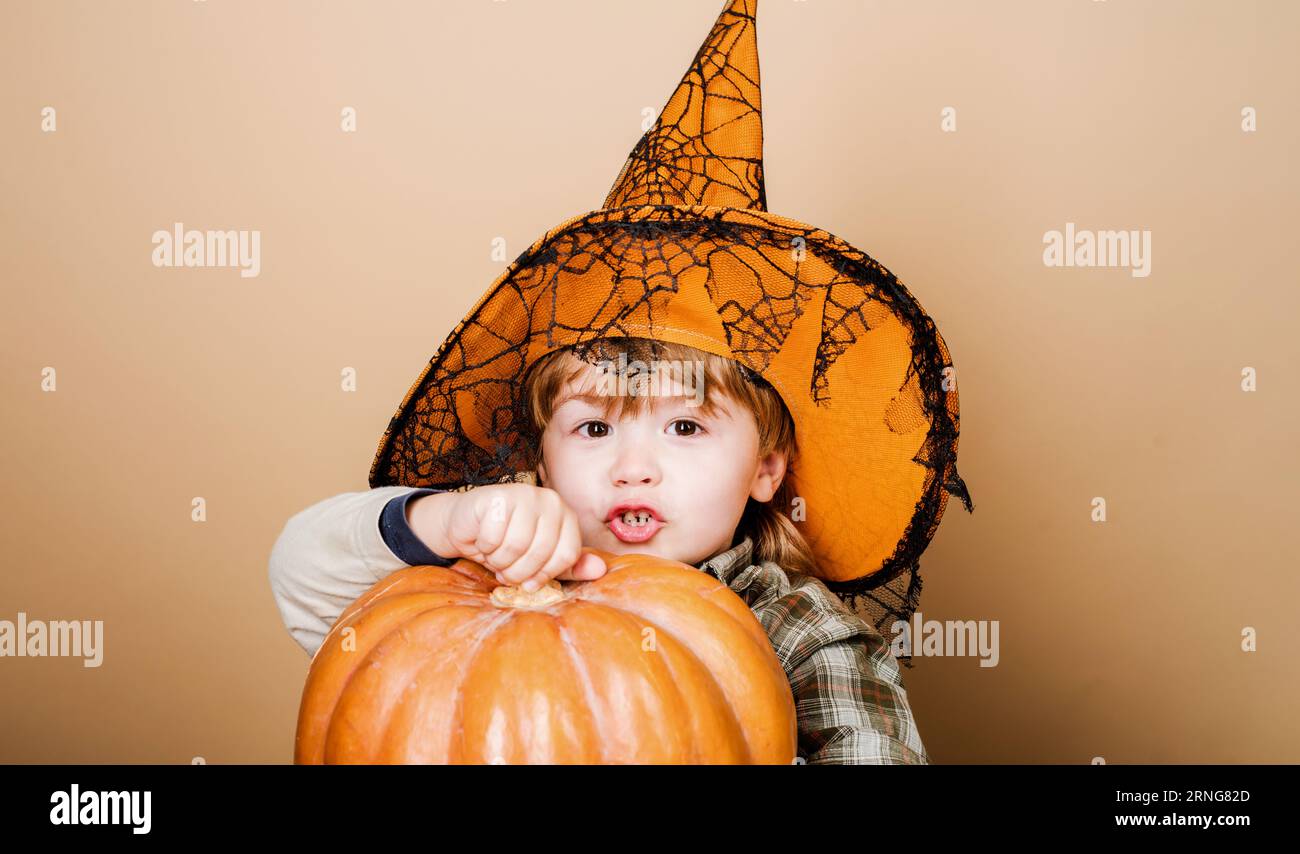 Halloween kid in magic hat with pumpkin. Cute boy in witch hat with Halloween jack-o-lantern. Halloween holiday celebration. Trick or treat. Little Stock Photo