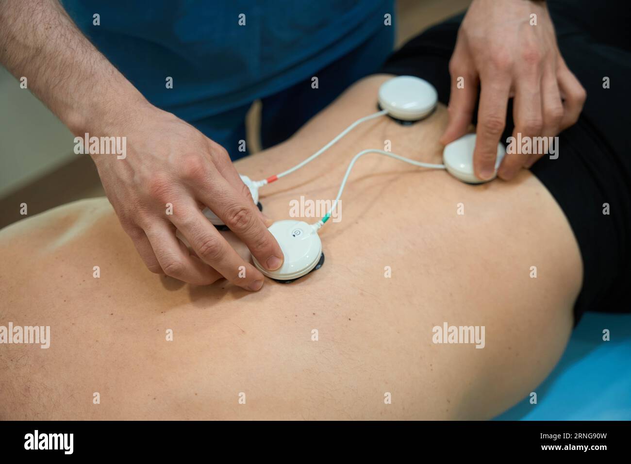 Electrical muscle stimulation in physical therapy. Therapist positioning  electrodes on a patient's knee Stock Photo - Alamy