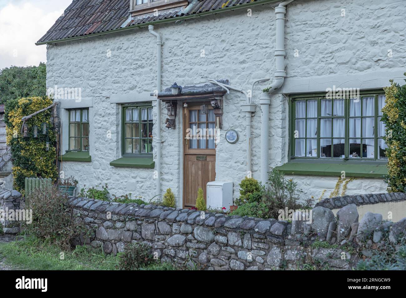 Front view of a seaside coastal cottage painted white with an old stone wall Stock Photo