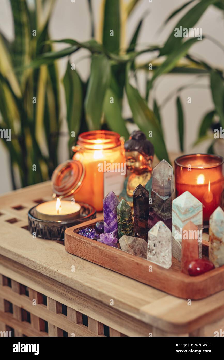 Various minerals and healing crystals on a wooden tray, buddha statuette and candles close-up. Meditation concept. Stock Photo