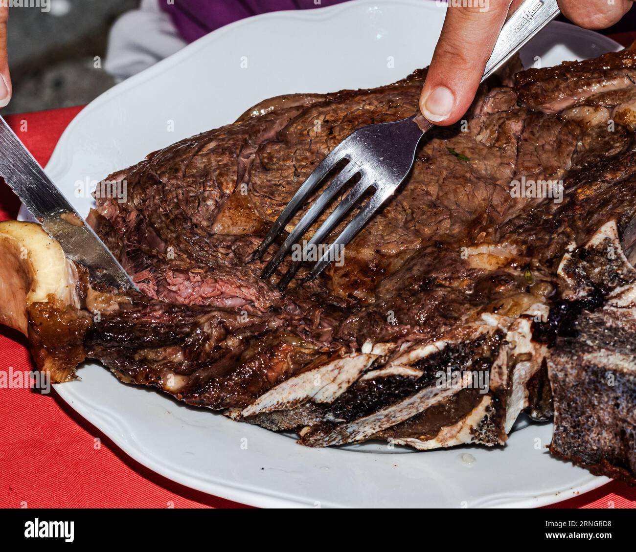 Culinary Mastery: Woman's Hands Slice into Succulent Barbecue Rib Steak with Precision Stock Photo