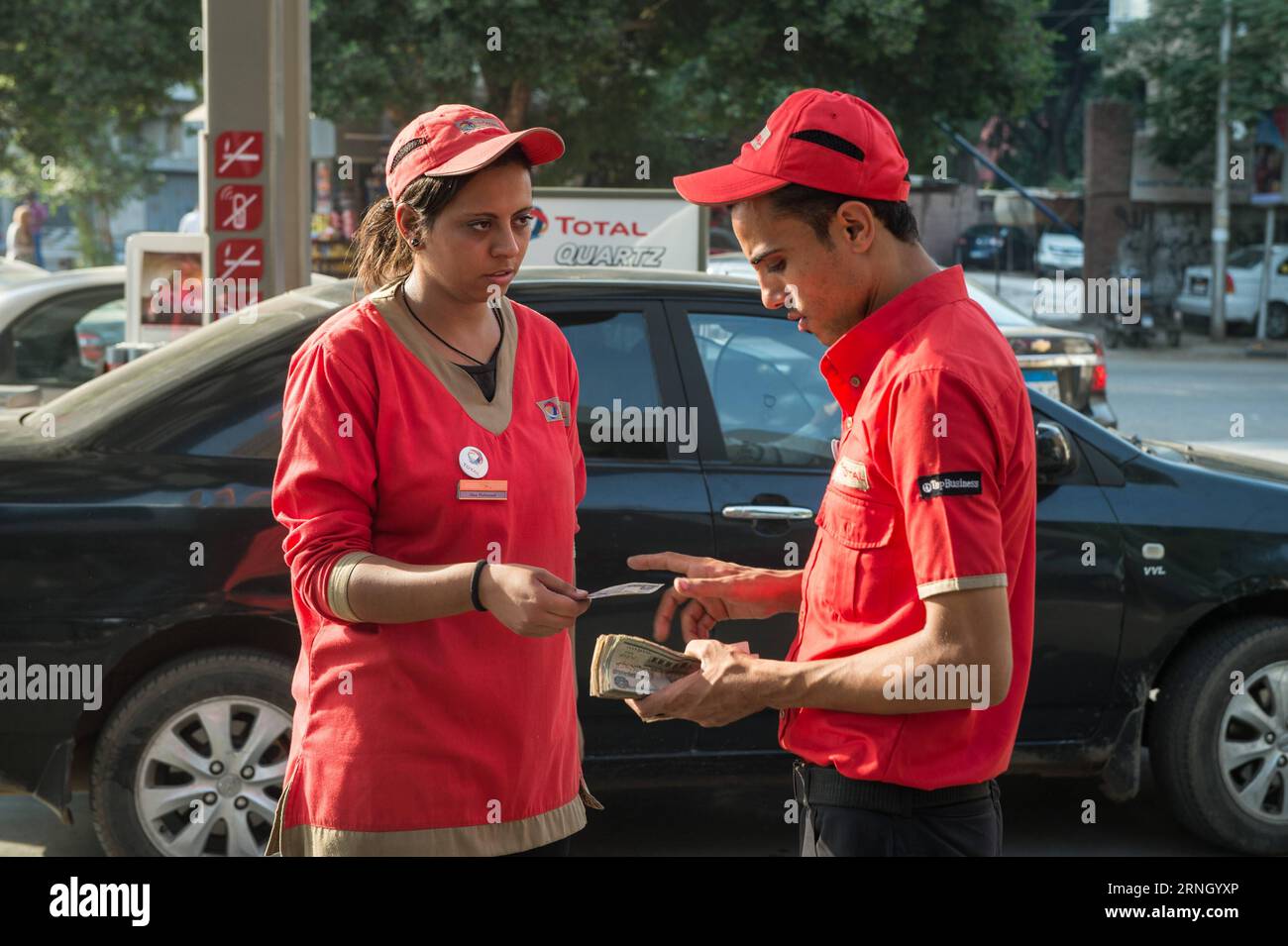 Ägypten - Weibliche Arbeitskräfte an einer Tankstelle in Kairo (161018) -- CAIRO, Oct. 18, 2016 -- Female and male employees work together at a gas station in Maadi district of Cairo, Egypt, Oct. 17, 2016. Dressed in red buttonless shirt and black pants uniform, 24-year-old veiled Hadeer Ashraf looked confident and swift while holding the fuel pump nozzle gun to serve the vehicles lined up at Total gas station near the Nile Corniche Street in Maadi district southwestern the Egyptian capital city of Cairo. ) (yk) EGYPT-CAIRO-GAS STATION-FEMALE WORKERS MengxTao PUBLICATIONxNOTxINxCHN   Egypt Fem Stock Photo