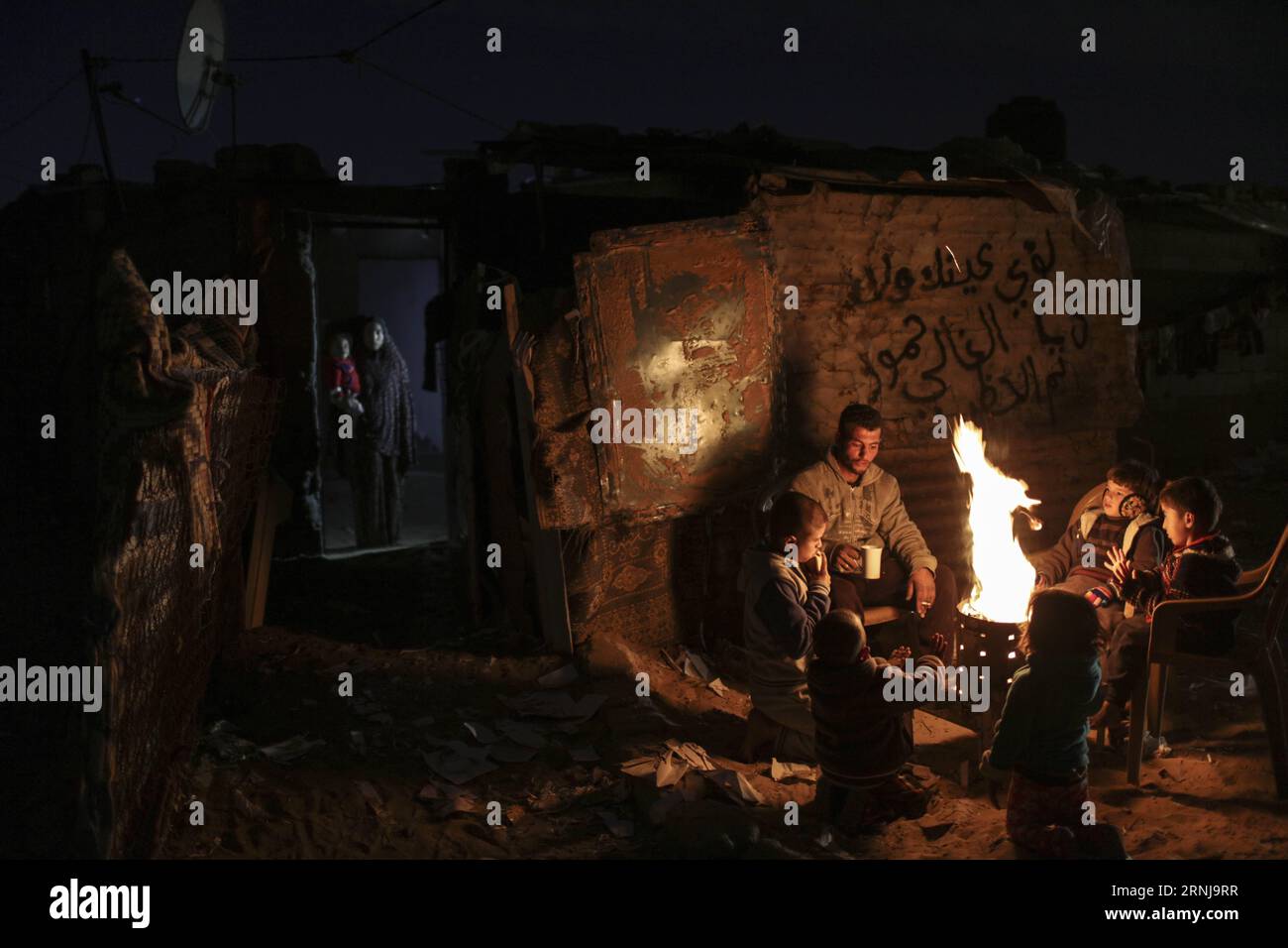 A Palestinian family warm up around a fire during a power outage ...