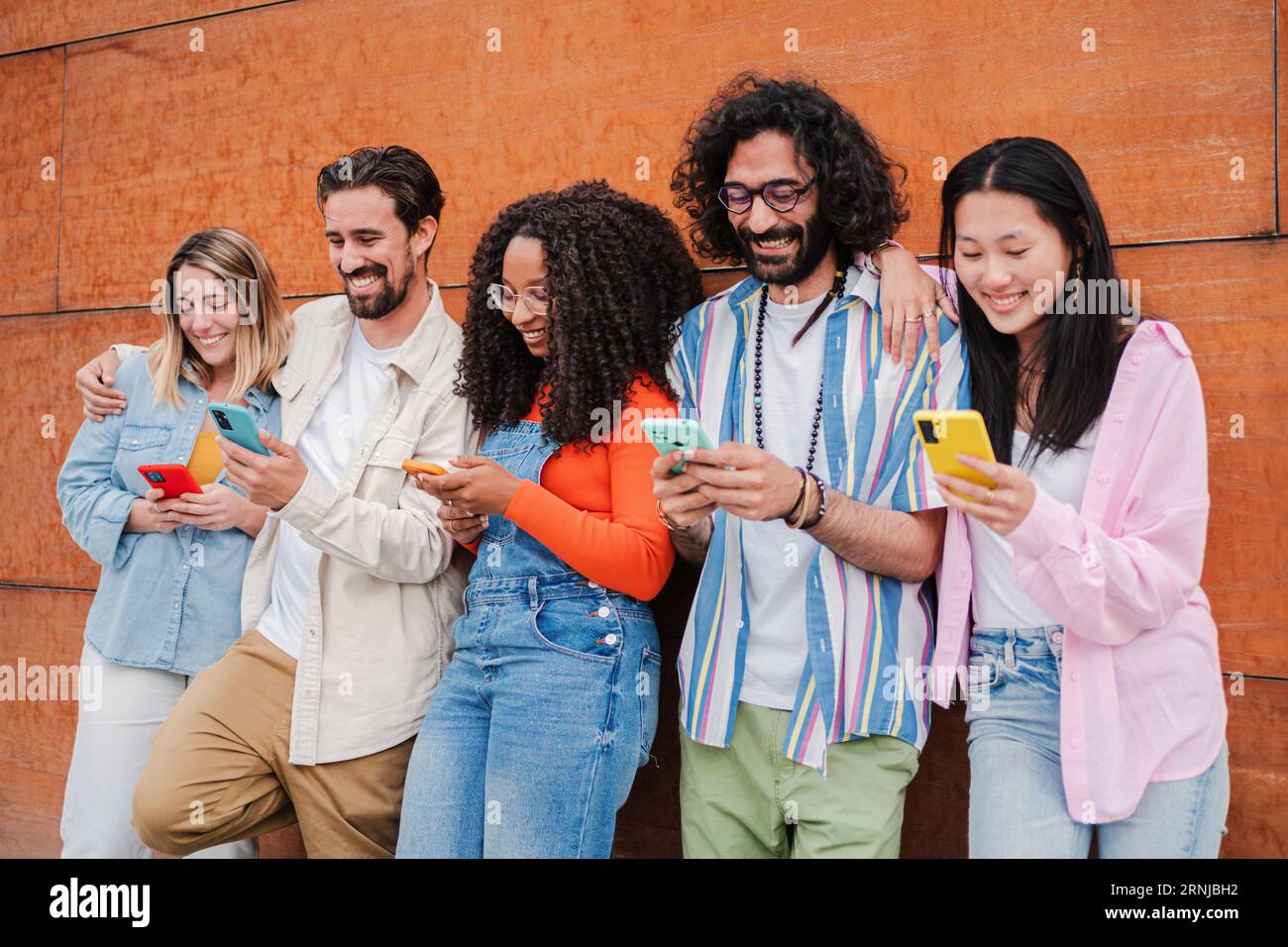 Group of friends having fun using a cellphone to browse on internet. Young  adult people sharing photos with smartphone social media application.  Buddies smiling and laughing watching the mobile phone. High quality