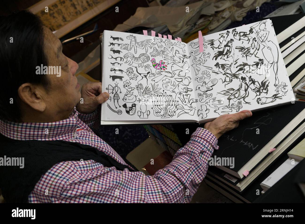 (170126) -- BEIJING, Jan. 26, 2017 -- Chinese artist Han Meilin, 80, shows his sketches at his studio in eastern district of Tongzhou in Beijing, capital of China, Jan. 24, 2017. Han, designer of the 2008 Beijing Olympic Games mascot Fuwa, has just finished the design of Chinese zodiac stamps for the upcoming Year of the Rooster. The set of Chinese Lunar New Year rooster stamps, issued earlier this month, contain two items showing a rooster striding proudly and a hen looking after her two chicks. Han applied rich color and elements of traditional Chinese painting to depict a happy family of ro Stock Photo