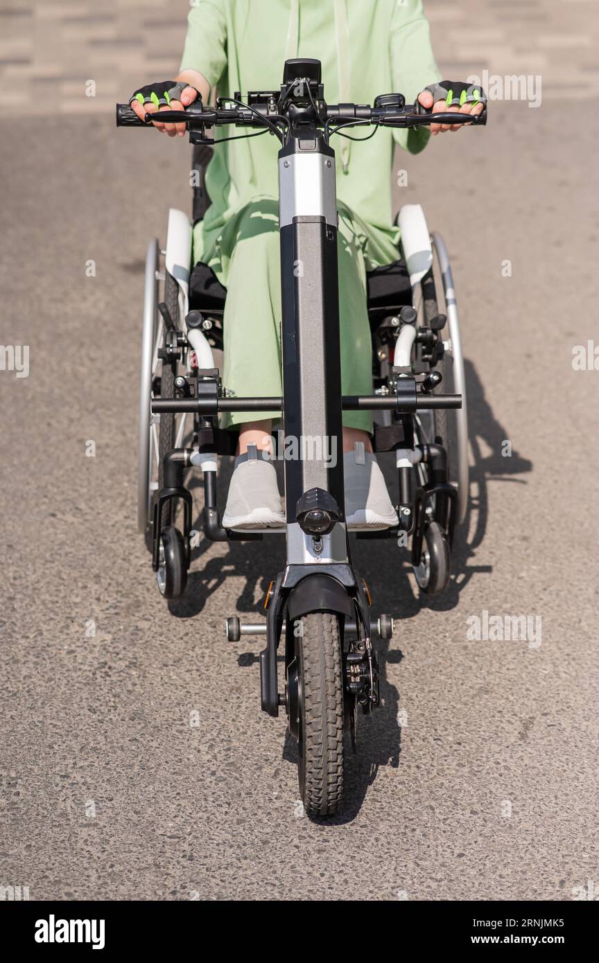 A woman in a wheelchair with an assistive device for manual control. Electric handbike Stock