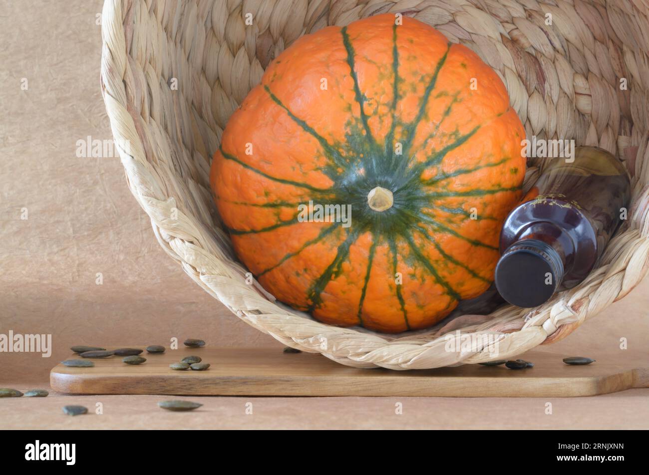 Still life with an orange round gourd, a bottle of gourd oil in a wicker basket in a horizontal format Stock Photo