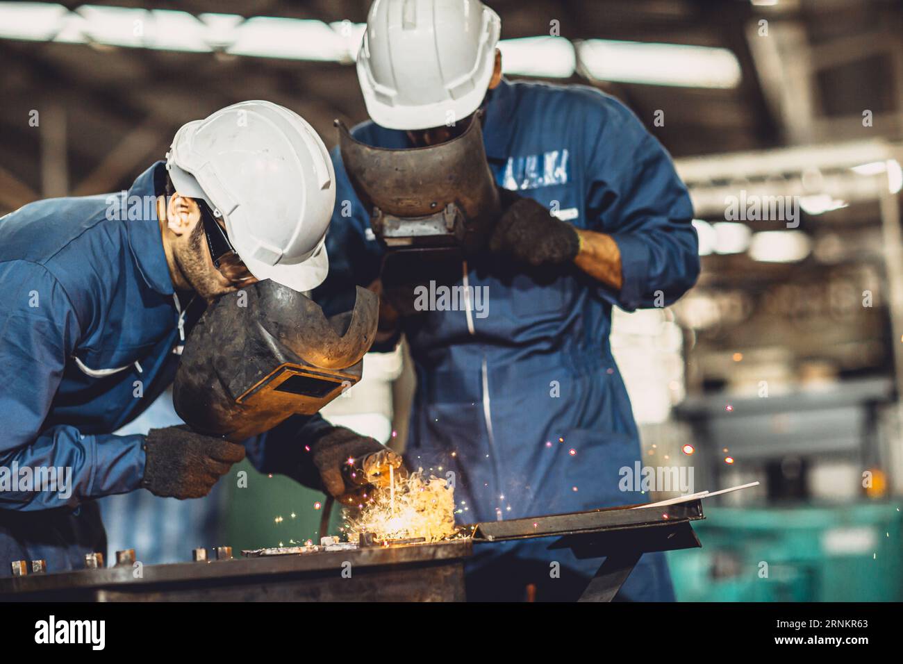 welding worker team working arc weld metal joint production in heavy