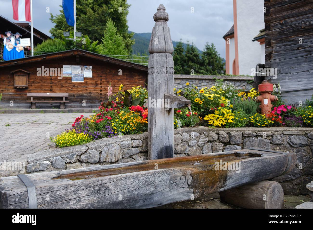 Traditional rustic wooden water fountain and trough in Alpine town centre of Alpbach, village in Western Austria. Stock Photo