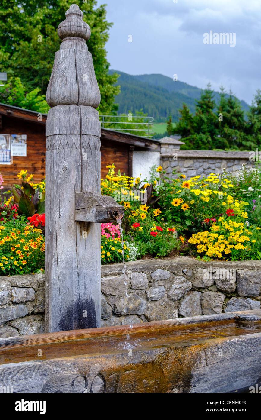 Traditional rustic wooden water fountain and trough in Alpine town centre of Alpbach, village in Western Austria. Stock Photo