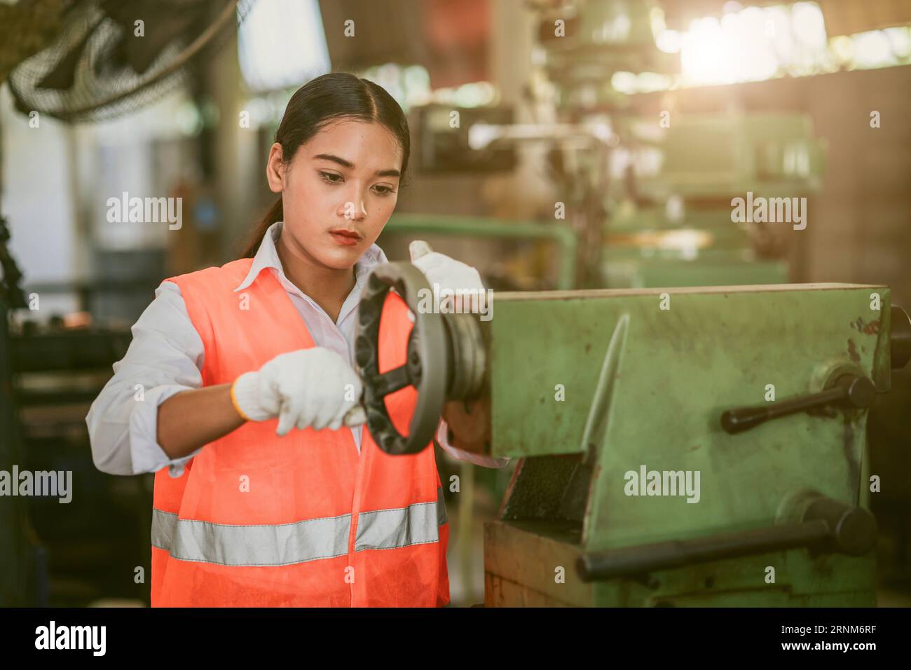 woman worker hard work focus working in heavy metal machine lathe milling factory industry Stock Photo