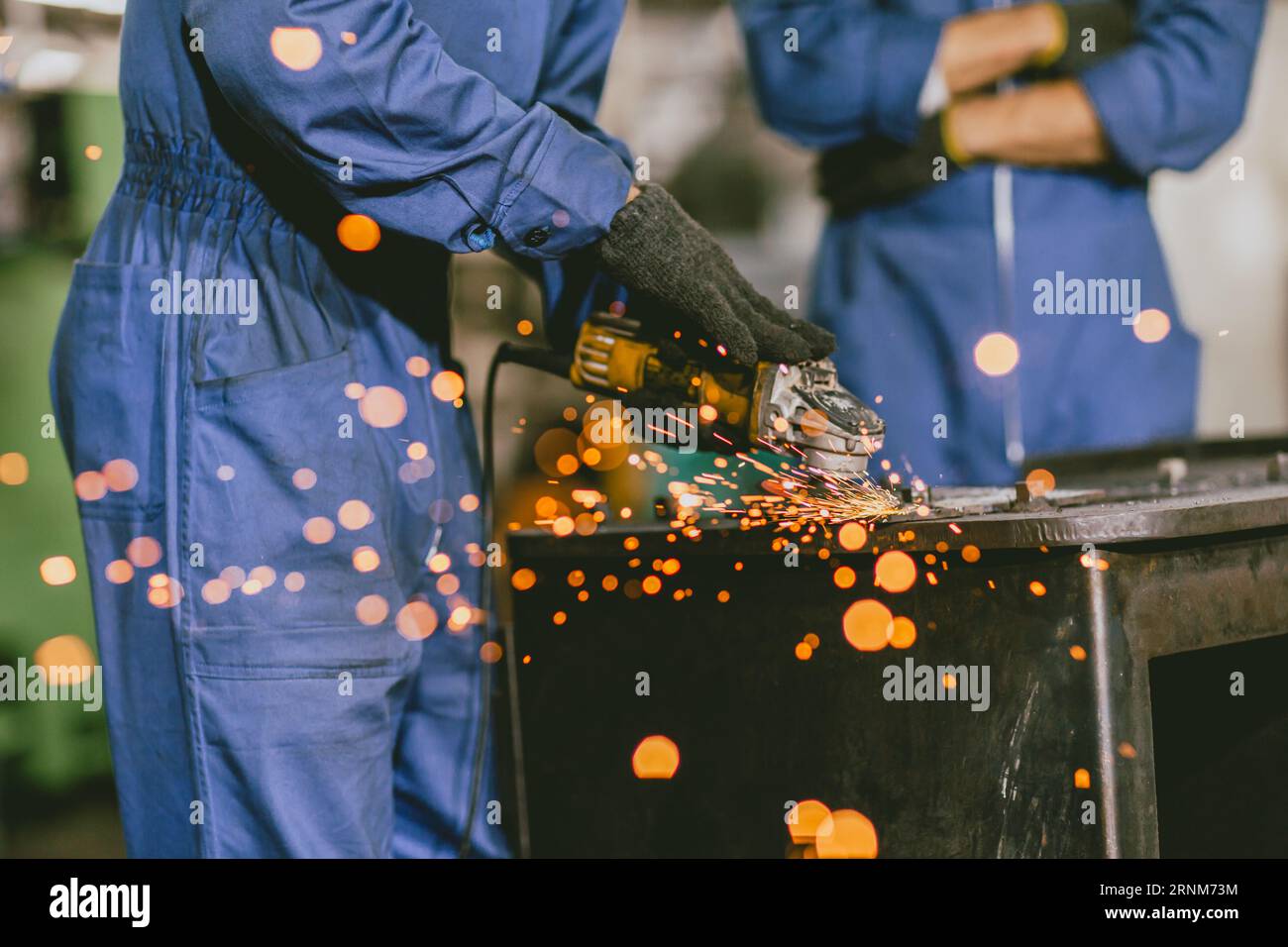 Industrial Worker Using Angle Grinder and Cutting a Metal Sheet. Contractor in Safety Uniform and Hard Hat Manufacturing Metal Structures.Heavy Indust Stock Photo